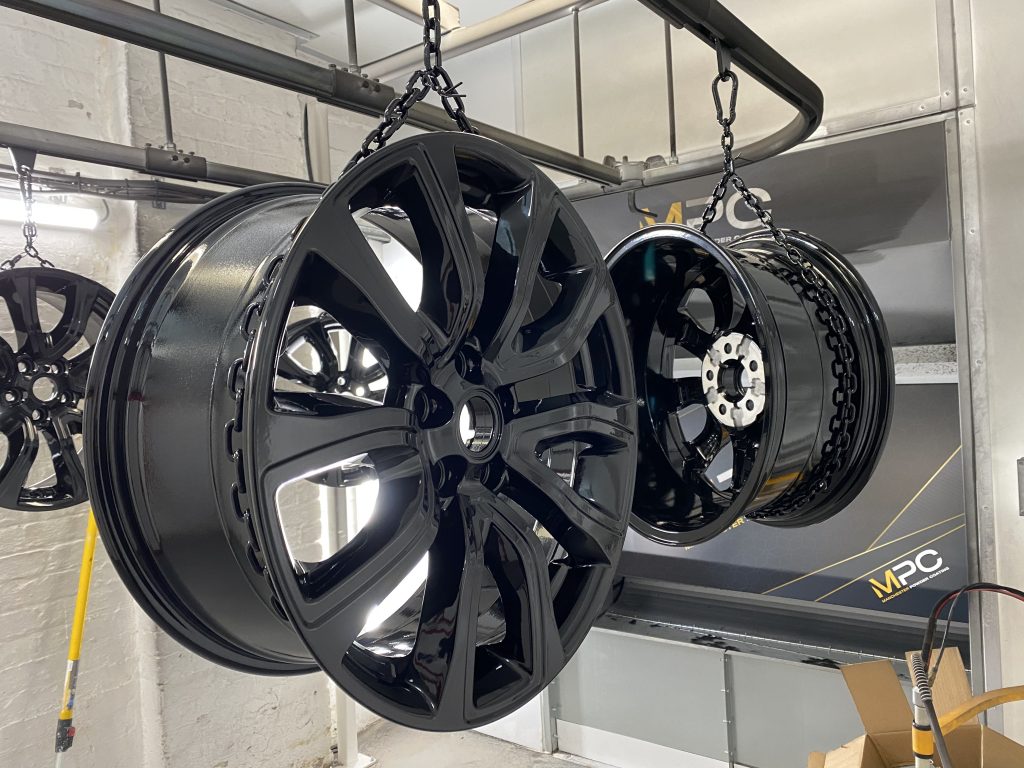 An image of black refurbished wheels hanging to dry