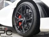 a McLaren wheel, refurbished to gloss black. It is a close up view of the wheel, with some of the white car visible either side.