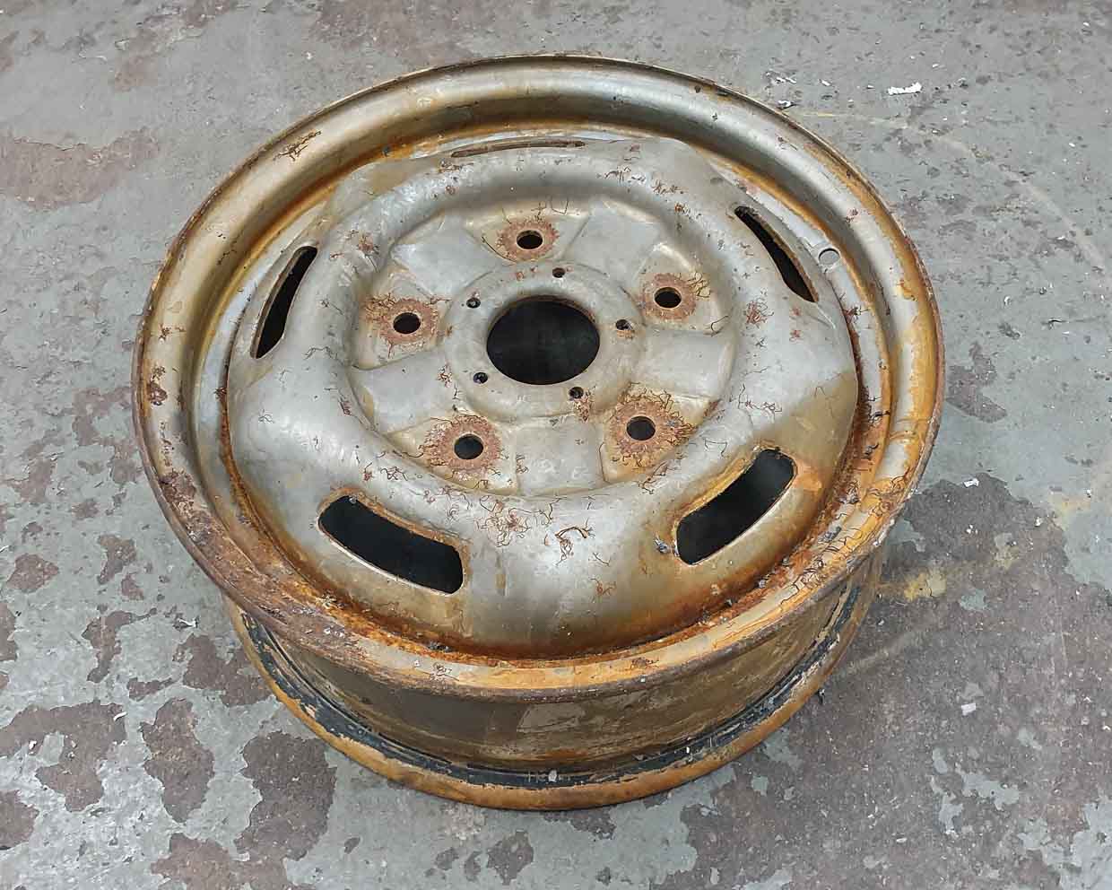 Steel wheel covered in rust awaiting to be refurbished and powder coated